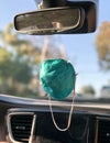 N95 face mask hangs from rearview mirror in car