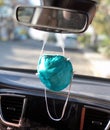 N95 face mask hangs from rearview mirror in car