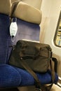 A N95 face mask or nose mouth protection mask on a seat in an empty commuter train with a business bag showing the mask is a perso