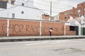 N old woman walking in front of a big graffiti in spanish. It means 6402 reasons to march.