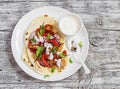 Naan bread with chicken vegetable stir fry and yogurt sauce on plate on rustic light wood background. Royalty Free Stock Photo