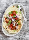 Naan bread with chicken vegetable stir fry and yogurt sauce on plate on rustic light wood background. Royalty Free Stock Photo