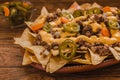 Nacho chips corn garnished with ground beef, melted cheese, jalapenos peppers in plate mexican spicy food in mexico