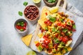 Nachos chips with cheese sauce, guacomole, salsa and vegetables on the board, top view. Party food concept Royalty Free Stock Photo