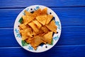 Nachos chips on mexican plate over blue