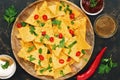 Nachos. Close-up of corn chips with variety of sauces ,chili pepper and greens on dark background. The view from the top, place fo Royalty Free Stock Photo