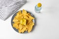 Nachos corn chips with cheese sauce on white table top view, soda water drink bottle, striped napkin Royalty Free Stock Photo