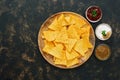 Nachos corn chips with variety of sauces on rustic dark background. The view from the top, place for text. Royalty Free Stock Photo