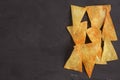 Nachos tortilla chips on black board on rustic wooden table. Flat lay, top view. Copy space. Royalty Free Stock Photo