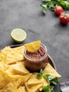 Nachos or tortilla with spicy tomato sauce on a plate with fresh vegetables and herbs on a dark background. Corn chips with salsa Royalty Free Stock Photo