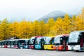 Nagano , Japan, 20 Oct 2017: The tour buses in parking lot in front misty Mountain view and range of yellow pine trees in autumn s