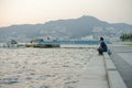 Nagasaki, Japan:August 31, 2016 - Portrait Asian man sitting on the seaside and looking out the ocean in the windy day. A man Royalty Free Stock Photo