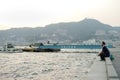 Nagasaki, Japan:August 31, 2016 - Portrait Asian man sitting on the seaside and looking out the ocean in the windy day. A man Royalty Free Stock Photo