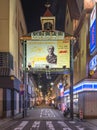 Gate of the ekimae shopping street of Nagasaki featuring a poster of thomas blake glover at night.