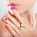 Nail art and design. Beautiful woman wearing make-up and pearl jewellery showing pink manicure with gems Royalty Free Stock Photo