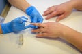 Nail care in the beauty salon. Beautician in medical gloves covers the client`s nails with a colorless varnish, close-up Royalty Free Stock Photo