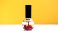 Nail care, cuticle oil in a beautiful bottle on a yellow background. Place for text