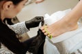 Dark-haired professional chiropodist holding nail file making pedicure