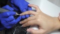 Nail master in blue rubber gloves preparating of nails for manicure. Beautician using electric nail file, cuticle pusher