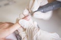 Nail master in rubber gloves make manicure using manicure machine tool (electric drill) on a woman hand finger nail. Healthcare b