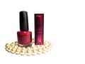 Nail polish, bard-colored closed lipstick and white pearl beads on a white background Royalty Free Stock Photo