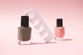 Nail polish bottles and pedicure sponge separator on pink background with copy space, vertical. Beauty product for manicure