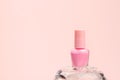 Nail polish small glass bottle on crystal podium on light pink background. Unbranded mockup with copy space, front view, template