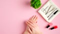 Nail salon table with manicure tools, nail polish bottles and female hands on pink background. Nail studio workspace concept Royalty Free Stock Photo