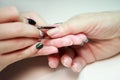 Nail service manicurist makes an elderly woman manicure with a metal tool - a lancet with a spatula at the end. Moving off the Royalty Free Stock Photo