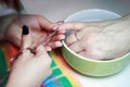 Nail service manicurist makes an elderly woman manicure with a metal tool - small scissors. Moving off the nail cuticle. reporting Royalty Free Stock Photo