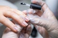 The nail service master does a manicure holds his finger and applies a transparent gel polish to protect the nail Royalty Free Stock Photo