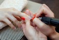 Nail technician saws and attaches a nail shape during the procedure of nail extensions with gel in the beauty salon.