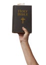 Naked arm raised into the air with hand reaching up holding the Holy Bible book of Chistianity Royalty Free Stock Photo