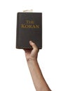 Naked arm raised into the air with hand reaching up holding the muslim Koran holy book of Islam