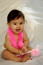 Baby sitting and smiling with pink feathers Royalty Free Stock Photo