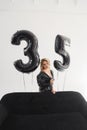 a naked blonde with tattoos in a black coat by a black sofa. birthday Royalty Free Stock Photo