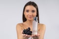 Selective focus. Naked brunette with fresh grape and grape seed oil in bottle. Skin care cosmetic product for poster