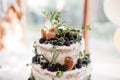 Naked cake. Wedding cake with berries, figs and twigs green.
