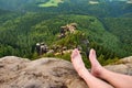 Naked male sweaty long legs on peak of sharp rock above valley.