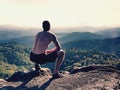 Naked man stay in black pants at the top of mountain. Hiker watch the morning hilly landscape