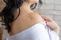 Naked shoulder woman with dark hair in white shirt. Skin covered with moles