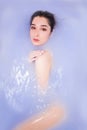 Naked woman in a bath with purp water. Spa and Wellness treatments