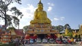 Austin Mini cooper and classic car parked in Thai temple with golden buddha statue and blue sky background.