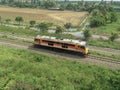 Single orange diesel engine locomotive drives on the railway pass through the rice field