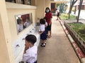 Nakhon Ratchasima, Thailand - July 2, 2020: Younger students in Nakhon Ratchasima wash up under supervision of a teacher as school