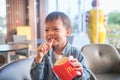 Nakhon Sawan, THAILAND - December 27, 2019: Cute Asian toddler boy eating french fries at McDonald`s restaurant, McDonald`s is