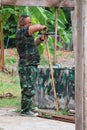 A soldier, a carpenter, is hammering wood. in house building, outdoor, carpentry work