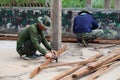 A soldier, a carpenter, is hammering wood. in house building, outdoor, carpentry work