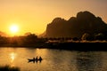 Nam Song River at sunset with silhouetted rock formations and kayakers in Vang Vieng, Laos Royalty Free Stock Photo