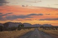 The desert road of Namatjira Drive in the Red Centre region of Northern Territory, Australia during sunset.